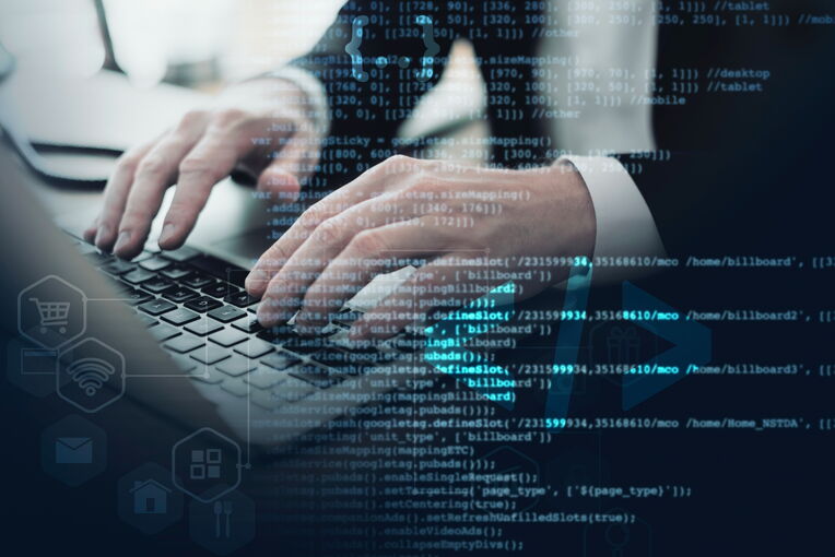 Hände tippen auf einer Laptop-Tastatur, überlagert von Code und Symbolen für Online-Shopping, WLAN und Apps. Veranschaulicht die digitale Welt, in der Structured Data Testing Tools relevant sind.