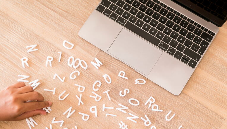 Hände und Buchstaben auf Holztisch